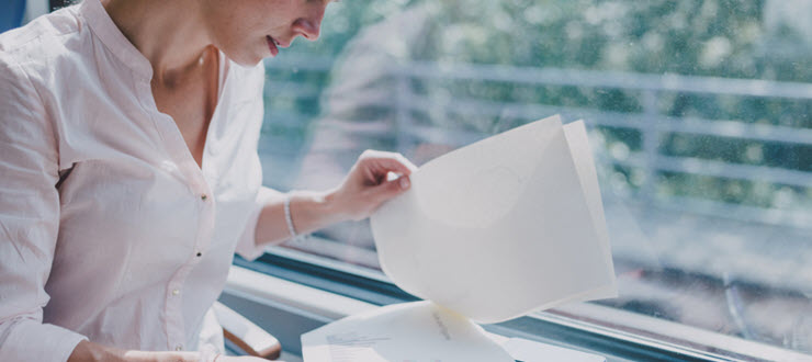 woman looking through application paper in front of window